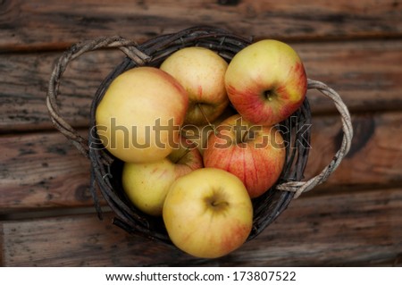 A bushel of red apples in a rustic wooden basket