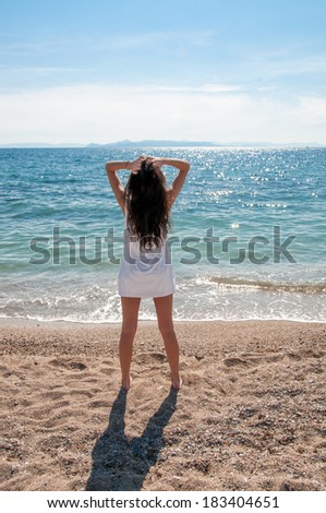 a woman standing on the beach watching the sea