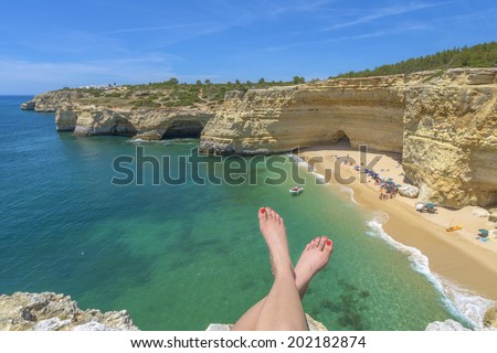 Tourist enjoying a beach view from a cliff in Algarve, Portugal