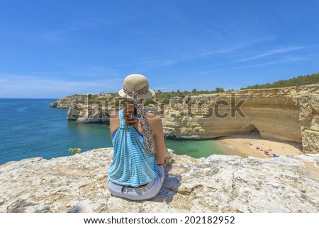 Young female tourist enjoying a beach view from a cliff in Algarve, Portugal