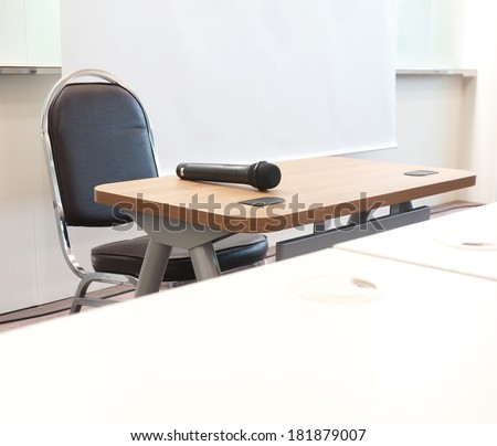The meeting room has tables, chairs, overhead projector, microphone, speakers or a scene for the upcoming presentation.