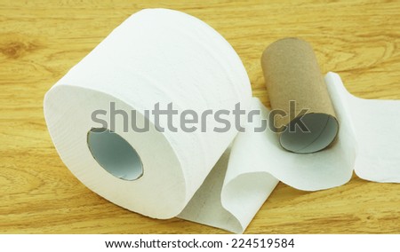 Roll of toilet paper and a core of rolls, placed on the wooden floor.