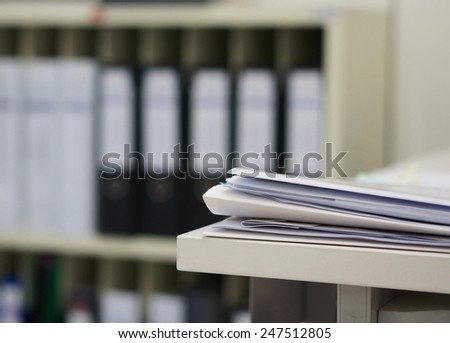 Many papers orderly arranged in a file shelves. And some are still on the table.