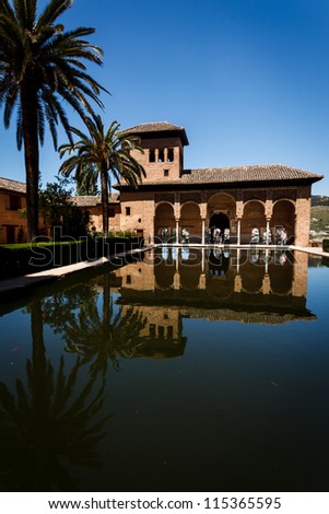 GRANADA, SPAIN - APRIL 27, 2010: the pavilion with arched portico by pool and tower and palm trees at the Palacio del Partal in Alhambra with Lion Patio reopened on April 27, 2010 in Granada, Spain.