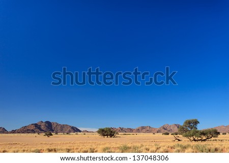 Row of tall Namib desert red sand dunes viewed in distance from highway. This desert is the oldest in the world completely devoid of surface water.