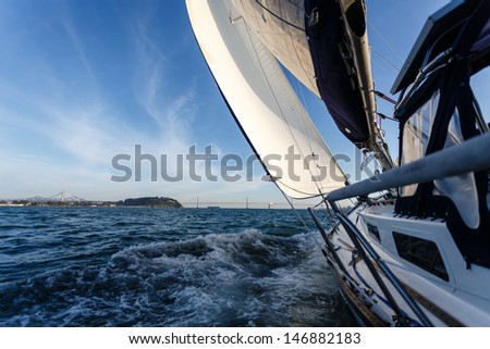 Side view of racing sailboat as it heads for the Bay Bridge in San Francisco Bay on a sunny day