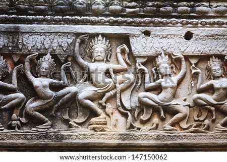 Row of stone aspara dancer carvings on the walls of an ancient temple of Angkor Wat in Siem Rep, Cambodia.
