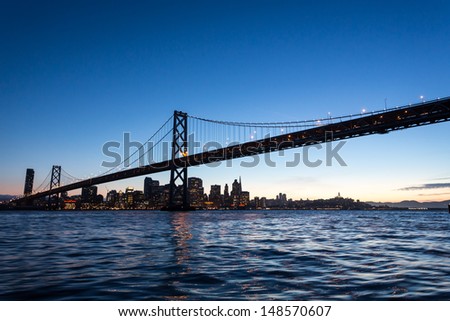 Bay Bridge spans San Francisco Harbor to Oakland on a sunny day at sunset