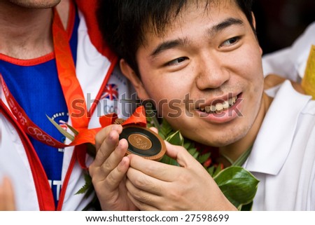 BEIJING - AUGUST  24: Chinese spectator holds Tony Jeffries Olympic bronze medal. Jeffries represents Great Brittan\'s in the men\'s light heavyweight boxing division August 24, 2008 in Beijing, China.