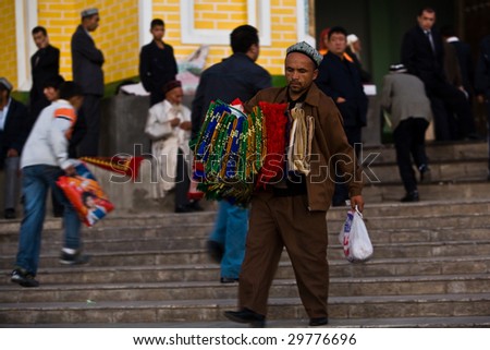KASHGAR, CHINA - OCT. 2: Uyghur man sells colorful prayer carpets on the steps of Id Kah Mosque before Ramadan services October 2, 2008 in Kashgar,  Xinjiang province western China.