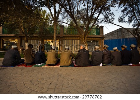 KASHGAR, CHINA - OCT 2: Muslim men sit in a row outside Id Kah Mosque to pray October 2, 2008 in Kashgar,  Xinjiang province western China. The mosque is usually full during Ramadan prayer service.