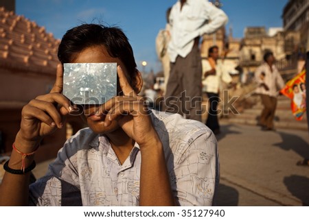 VARANASI, INDIA - JULY 22: A young Indian man uses a dark solar filter to view the full solar eclipse July 22, 2009 in Varanasi, India.