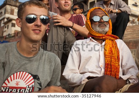 VARANASI, INDIA - JULY 22: Indian man and western tourist watch solar eclipse together, wearing dark glasses July 22, 2009 in Varanasi, India.