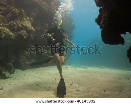 GREAT BARRIER REEF, AUSTRALIA - OCT 28: Scuba diver with camera swims in a coral tunnel October 28, 2009 in Great Barrier Reef, Australia.