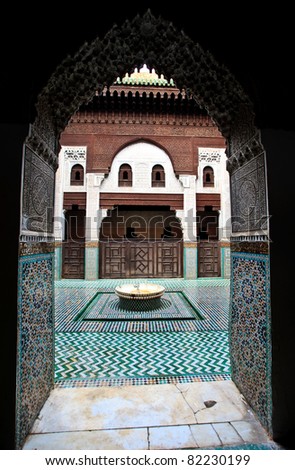 Intricate and symetrical interior of Muslim madrasah school framed by arched entrance in Meknes, Morocco.