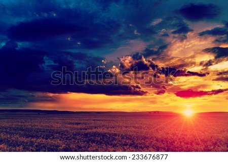 Dramatic sunset over fields with clouds during late summer