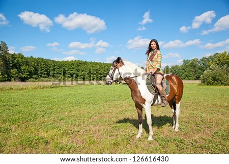 A young girl dressed as an Indian rides a paint horse
