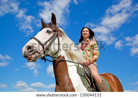 A young girl dressed as an Indian rides a paint horse. Focus on horses face.
