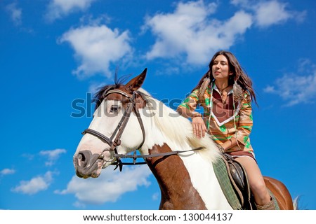 A young girl dressed as an Indian rides a paint horse. Focus on horses face.