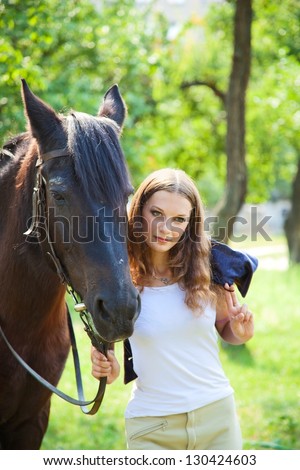 Young girl walking with a horse in the garden.