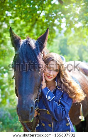 Young girl walking with a horse in the garden.