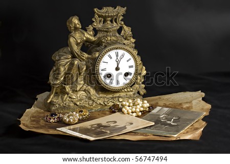 Antique clocks, jewelry and photographs on a dark background