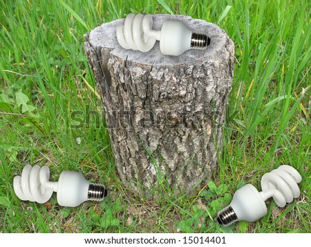 Ecological concept energy saving light bulb on old stub of a tree in the grass