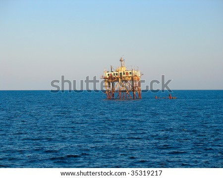 old abandoned sea rusty drilling platform in the sunset
