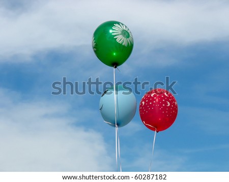Three colorful helium-filled balloons over blue sky background