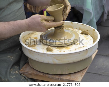 Hands of a potter, taking ready earthen jar from the circle