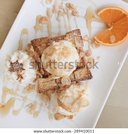 Top view of butter honey toast with vanilla ice cream topping with honey and orange. Soft filter style.