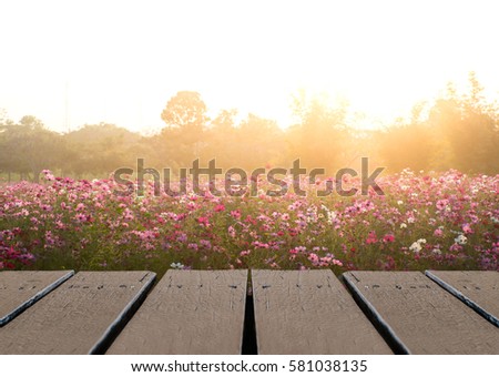 Wood floor table scene of beautiful sunset sunrise sky over flower field. Holiday vacation travel relax background with copy space for decorate design.