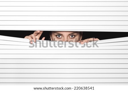 Woman Looking Through Venetian Blinds