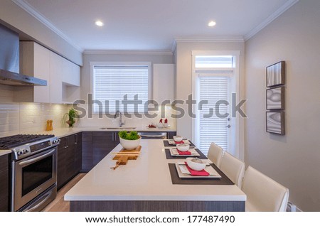 Modern kitchen interior with island and cabinets in a luxury house set for dinner