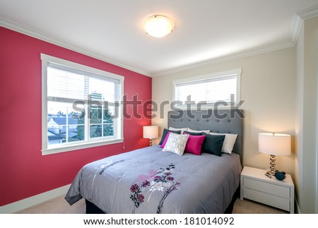 Modern bedroom interior with a red wall, designer pillows, and a floral duvet cover in a luxury house