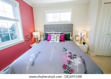 Modern bedroom interior with a red wall, designer pillows, and a floral duvet cover in a luxury house
