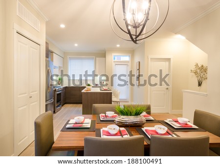 Modern dining room table with plates and bowls in a house, hotel with a kitchen in the background. Interior design.