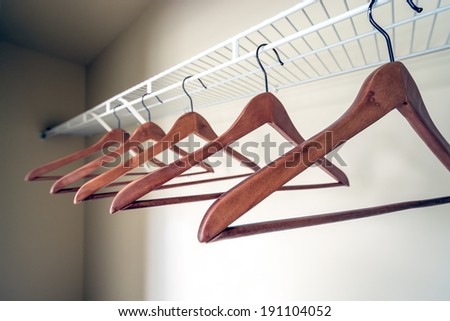 Coat hangers on a clothes rail in an empty closet.