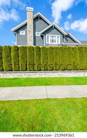 Beautiful house behind green hedge fence. Landscape trimming design. House exterior.