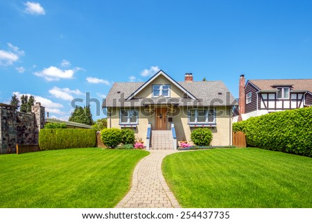 Cozy house with beautiful landscaping on a sunny day. Home exterior.