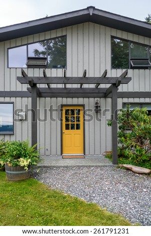 Entrance of a luxury, mid-century modern cottage house with yellow door