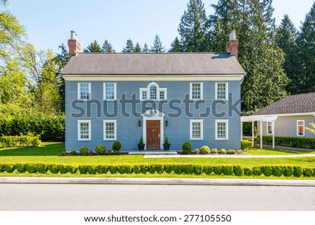 Luxury blue house with beautiful landscaping on a sunny day. Home exterior.