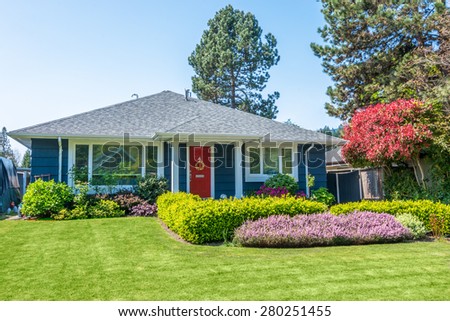 Cozy blue house with beautiful landscaping on a sunny day. Home exterior.