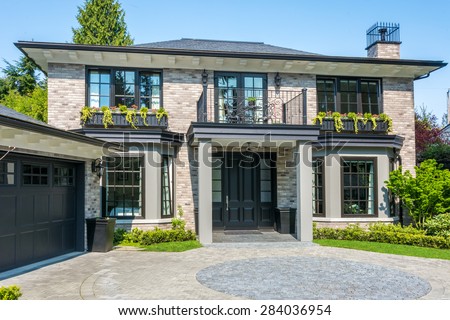 Gorgeous luxury house with a balcony and beautiful landscaping on a sunny day. Home exterior.