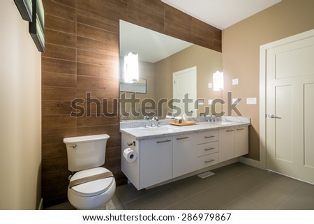 Interior design of a luxury bathroom with a wood wall and a large mirror.