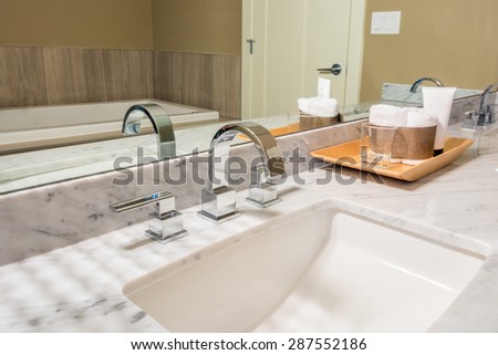 Fragment of a modern luxury bathroom with sink, wooden tray and large mirror. Interior design.