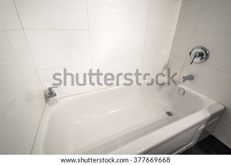 White bathtub in a tiled bathroom. Interior design.