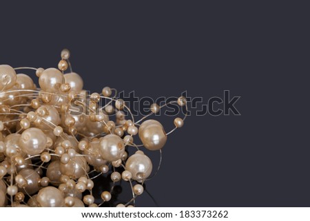 A string of differently sized pearls, bound together with a nylon string, shot in the left corner of a black surface.