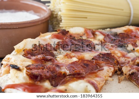 A great composition of a peperoni pizza pie, a bowl of flour and a bunch of spaghetti.