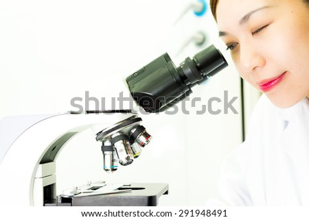 Asian Researcher looking through a Microscope in Biochemistry Lab